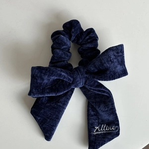 Dettaglio di scrunchie con fiocco in velluto blu scuro ed elegante ricamo Alline sul nastro