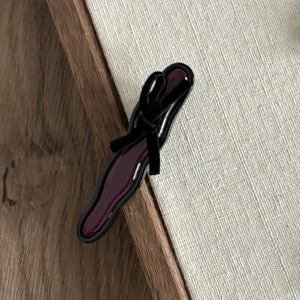 Detail shot of a vintage wine red resin hair clip with a black velvet bow on linen fabric