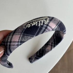 Dettaglio del cerchietto imbottito a quadri rosa e blu con ricamo a mano in bianco