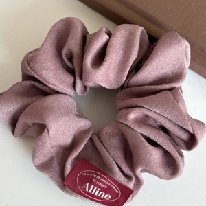 Elegante scrunchie in seta rosa antico con etichetta Alline e consistenza morbida