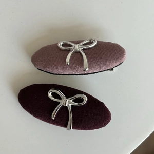 Dettaglio di fermagli in tessuto rosa e rosso scuro con fiocchi in metallo argento