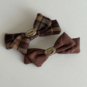 Detail of plaid and brown fabric bow hair clips with Alline brand metal buckle detail