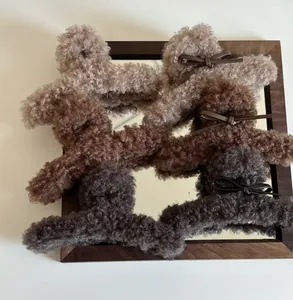 Détail de pinces à cheveux en peluche beige et marron avec nœuds fins en cuir