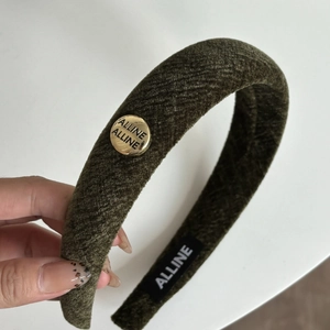 Detail view of moss green velvet headband with gold brand logo and striped texture