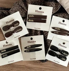 Detailed view of coffee-colored acrylic hair clips with gold lettering on display cards