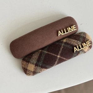 Close-up of vintage brown plaid and solid fabric hair clips with gold ALLINE metal letters