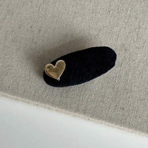 Close-up of velvet hair clip featuring a golden heart-shaped metal with Alline engraving