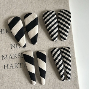 Set of 8 minimalist black and white striped cloth BB hair clips on a linen background