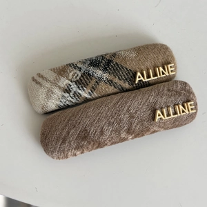 Close-up of checkered fabric and brown velvet hair clips with golden metal lettering