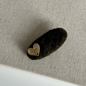 Close-up of deep green velvet hair clip with golden heart detail engraved with Alline text