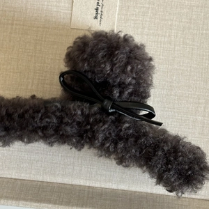 Gros plan sur la pince à cheveux en peluche gris foncé avec nœud en cuir noir chic