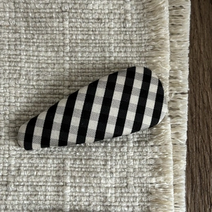 Classic black and white checkered fabric BB hair clip on a bohemian textured woven mat