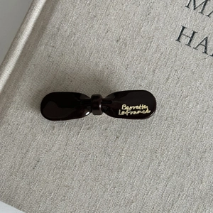 French retro coffee brown bow hair clip with gold logo on textured fabric book
