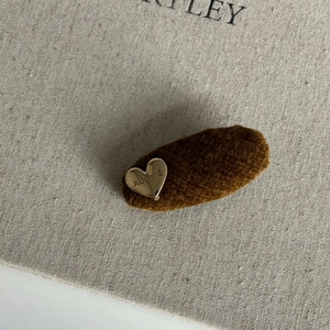 Detailed close-up of velvet hair clip featuring a gold heart with engraved lettering