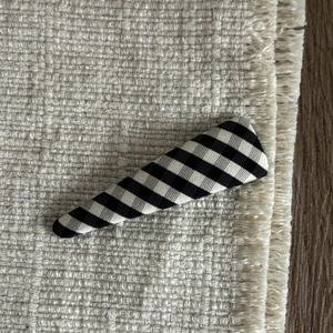 Detail of fabric-covered checkered BB hair clip with black and white gingham pattern