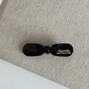 Close-up of black glossy bow hair clip with gold Barrette La France lettering details