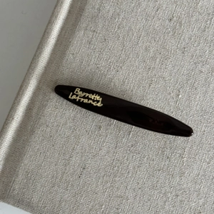 Detailed macro view of high-gloss coffee brown acetate hair clip with golden Barrette La France text