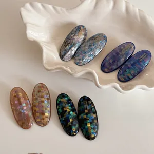 Detailed macro view of checkered resin hair clips in mosaic patterns on shell tray
