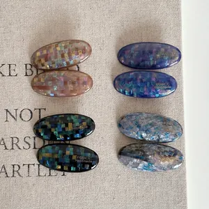 Set of 8 glitter checkerboard oval hair clips in assorted colors on a beige fabric