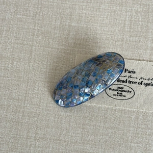 Elegant blue mosaic shell oval hair clip with shimmering checkerboard pattern on fabric
