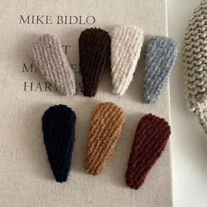 Knitted teardrop BB hair clips set in warm autumn brown tones on book background