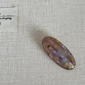 Close-up of oval resin hair clip featuring colorful mosaic sequins and handmade text