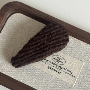 Detail of dark brown knitted BB hair clip with thick woolen texture and retro style