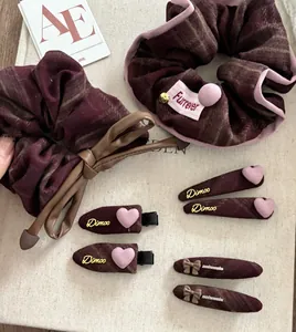 Detail of burgundy plaid hair accessories set including bows, scrunchies and heart clips