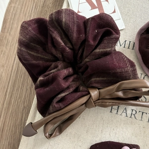 Detailed view of dark red plaid scrunchie with brown faux leather bow tie accent
