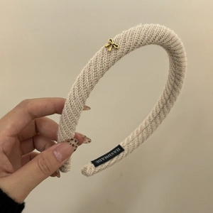 Minimalist beige knitted twill headband with small gold bow detail and handmade tag