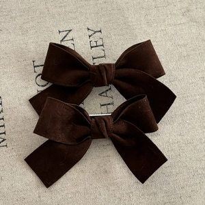 Set of two brown velvet bow hair clips with long ribbons on rustic linen background