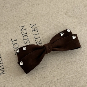 Detail of a brown velvet bow hair clip with sparkling heart-shaped rhinestones