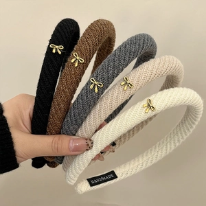 Set of five knitted headbands with elegant golden bow accents in various neutral colors