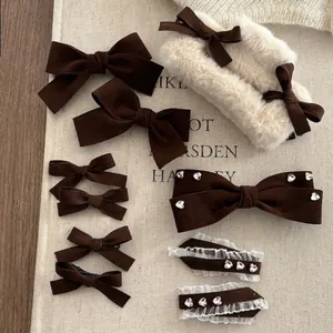 Brown velvet bow hair clip set with heart rhinestones and lace detail on beige fabric