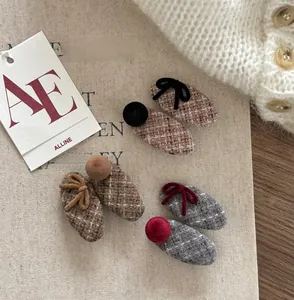 Close-up of wool plaid hair clips with velvet bows and plush balls in warm autumn colors