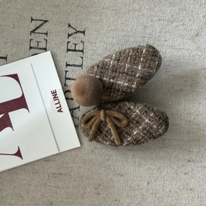 Brown tweed hair clip set with plush ball and bow decoration on textured canvas