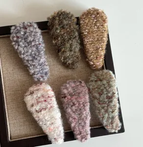 Detail of six knit plush BB hair clips in Morandi colors displayed on a wooden tray