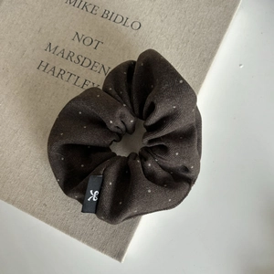 Brown polka dot scrunchie hair tie on a minimalist book for elegant ponytail styling