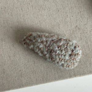 Close-up of retro fuzzy plush hair clip with grey and red woven textured fiber detail