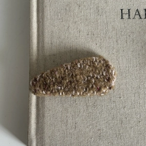 Macro shot of brown plush fuzzy BB hair clip on a book edge with warm cozy lighting