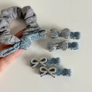 Close-up of blue denim knit bow hair clips and grey velvet scrunchie set with pearls