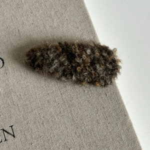 Macro detail of plush lamb wool BB hair clip in dark brown and beige mixed texture
