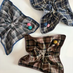 Detail of three plaid knit scrunchies with decorative cloth buttons in assorted colors