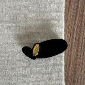 Minimalist black velvet hair clip with a gold Makeawish metal plate for women