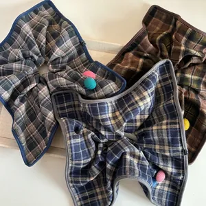 Three oversized plaid hair scrunchies with colorful crochet balls on light beige tray