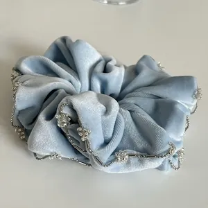 Detailed macro view of light blue velvet scrunchie with elegant silver bead chain edges