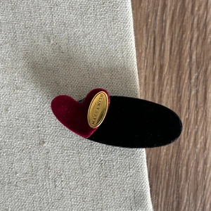 Detail of red velvet heart and black oval hair clip with gold Make a Wish engraving