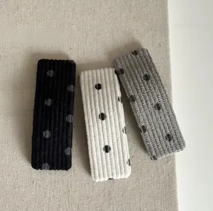 Détail de barrettes à cheveux en velours à pois noir blanc et gris en tissu côtelé