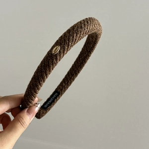 Brown knit headband with golden Wings logo metal tag and thick padded structure