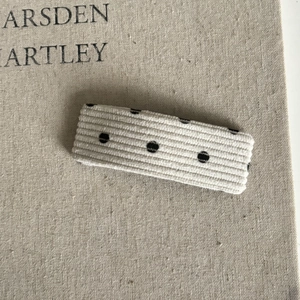 Détail d'une barrette rectangulaire en velours côtelé crème avec motif à pois noirs